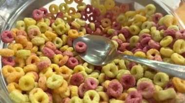 Renkli mısır gevreğini bir kase süte dolduran kişi. Yukarıdan yakın çekim. Yüksek kalite 4k görüntü