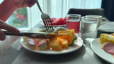 Kahvaltı için meyveler bir parça papaya 'yı bıçak ve çatal meyveleriyle doğradı oteldeki tropikal kahvaltılarda her yöne dikkatsizce uçtu. Yüksek kalite 4k görüntü