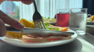 Bıçak ve çatalla yemek. Sunny Plate piercing prosciutto bonfile fileto domuz eti. Sağlıksız et. Yüksek kalite 4k görüntü