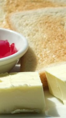 Bir küp donmuş tereyağını al ve tostun üzerine çilek reçelinin yanına koy. Yüksek kalite 4k görüntü