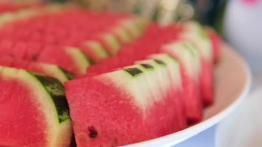 Karpuz dilimleri, sulu kırmızı eti ve taze yeşil kabuğu sergiliyor. Parlak renkler ve doğal dokular sağlıklı yemek severler için mükemmel bir seçim. Dilimlenmiş karpuz tabağı