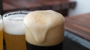Bardakta köpüklü bira, köpükle dolu. Bardakta alkollü altın bira. Siyah arka planda taze bira. Yüksek kalite 4k görüntü