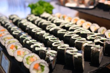 Sushi dürümleri pirinç, yosun, karides, salatalık ve balık yumurtası Japon mutfağının çekici bir sunumunu oluşturuyor. Japon suşisi ve makaralı makro görüntüler. Yüksek kalite 4k