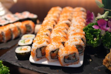 Beyaz sos üzerine serpiştirildiği için kaplanmış suşi rulolarının yavaş çekim yakın çekimi. Yüksek kalite 4k görüntü