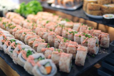 Beyaz sos üzerine serpiştirildiği için kaplanmış suşi rulolarının yavaş çekim yakın çekimi. Yüksek kalite 4k görüntü