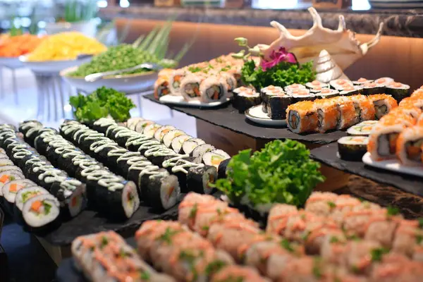 Restoran masasında zarif bir şekilde sergilenen çeşitli suşi ruloları Japon mutfağına lezzetli bir dalış sunuyor. Lezzetli bir deneyim. Taze balık, çıtır çıtır sebzeler. 