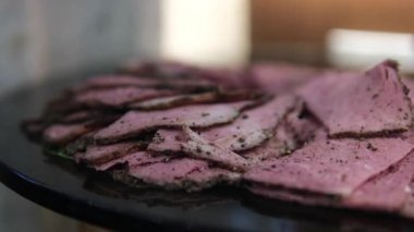 Beyaz adamın eli masaya ince dilimlenmiş jambonlu plastik paketler koyar. Kaya üzerinde doğranmış atıştırmalıklar için plastik ambalaj. Servis masasında ince jambon dilimlenmiş.. 