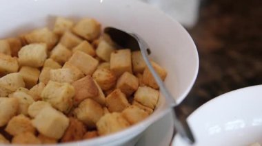 Kahverengi arka planda el yapımı beyaz ekmek küpleri dönüyor. Yemek arkaplanı. Son derece makro bir görüş. Ekmek, sarımsaklı ev yapımı ekmek. Tahta tabakta dönüyor..