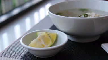 Limonlu çorbaya sıkışan el, Bangkok 'un hareketli restoranlarında bir kase Po' nun üzerine limon sıkıyor ve bulaşık tadını arttırıyor. Yüksek kalite 4k görüntü