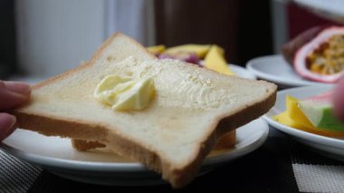 Tahtadaki bıçakla tostun üzerine tereyağı sürüyorum. Yüksek kalite 4k görüntü