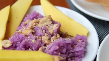 Fıstık ezmesi karışımı, mor pilav ve doğulu mango parçaları. Üzerine hindistan cevizi sütü serpilmiş pilav ve kavrulmuş fıstık. Tabakta servis edilen mangolu pilav. Sonraki yer mango.