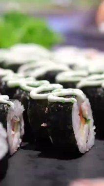 Sushi dürümleri pirinç, yosun, karides, salatalık ve balık yumurtası Japon mutfağının çekici bir sunumunu oluşturuyor. Japon suşisi ve makaralı makro görüntüler. Yüksek kalite 4k