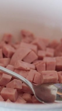 Beyaz zemin üzerinde kaşık tabağıyla pişirilmiş sosis mortadella küpleri.