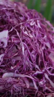 Bambu kesme tahtası üzerinde kırmızı lahana doğrama closeup görünümü. Sağlıklı vegan veya vejetaryen yemek