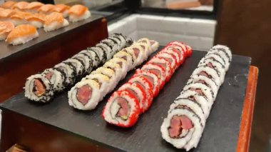 Tahta çubuklar karides krem peynirli kırmızı tobiko ile dolu lezzetli suşi ruloları topluyor. Restoranda suşi yiyordum. Makro görüntüler ağız sulandıran suşi rulosu. 