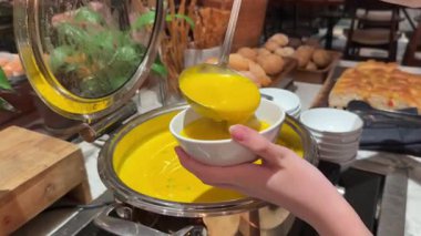 Sıcak sarı çorba, bir kepçeyle seramik kasede servis ediliyor. Yemek içeriği, yemek videoları, restoran tanıtımları ya da sosyal medya makaraları için ideal. kabak çorbası