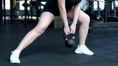 Spor kıyafetleri ve tesettürlü Müslüman bir kadın spor salonunda kettlebell ile ağırlık kaldırıyor. Yüksek kalite 4k görüntü
