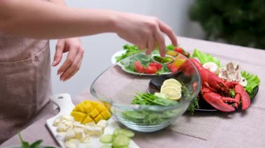 Salata standına salatalık ekle. Ebeveyn, ev hanımı ev mutfağında salata karıştırıyor. Modern anne yeşil salata hazırlar, farklı sebzeler ve sağlıklı beslenme kombinasyonları kullanır.