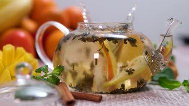 Çaya bir portakal dilimi at. Citrus, Closeup, Glass Teapot, Lemon and Lime at Table ile Nane Yaprakları koy. Yüksek kalite 4k görüntü