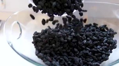 Siyah kuru üzümler ağır çekimde yavaşça tahta bir kaseye düşer. Kurutulmuş üzümleri yakından çek. Kurutulmuş meyve ve kuru böğürtlen. Yüksek kalite 4k görüntü