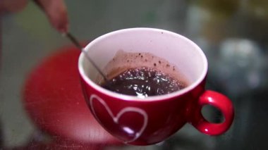 Sıcak çikolatalı Stirs Sugar 'ı Aromatik Kahve Fincanı' nda karıştırmak. Kişi Eli Karıştıran Sıcak Çikolata. Taze Sabah Kahvesi. Yakın çekim. Ağır çekim. Süt Sıcak Çikolatası Beyaz Kupada. 