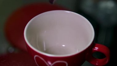 Kahve fincanındaki kaşıktan düşen kahve parçaları. Kahve tozu kaşıktan düşüyor. Taze Sabah Sıcağı. Sıcak çikolata, kırmızı kahve fincanı, bir fincana kakao dök. Yüksek kalite