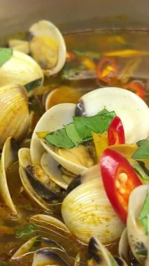 Baharatlı kırmızı sundubu jjigae siyah bir taş kasede, üzerinde yumuşak yumuşak tofu, yeşil sebzeler ve mantarlar var. Taze servis edilmiş, kaseden hala sıcak. Yüksek kalite 4k görüntü