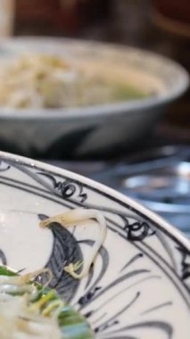 Soya lahanası, fıstık, yumurta, yeşil soğan ve limon dilimli geleneksel Asya eriştesi tabağı ahşap masadaki seramik kasede servis edilerek sokak yemeklerini temsil ediyor. Yüksek kalite 4k