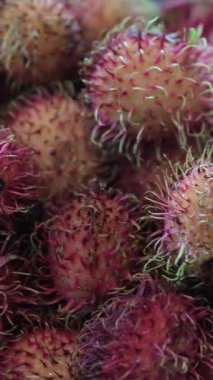 Rambutan meyvelerinin sepette yakın çekim videosu. Kamera dikenli kırmızı ve yeşil derilerini yakalar ve bu tropikal meyvelerin eşsiz dokusunu ve canlı renklerini gösterir. Yüksek kalite 4k görüntü