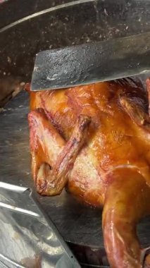 Kahverengi bir kesme tahtasının üzerinde gümüş bir bıçakla kızarmış ördek doğrayan biri. Yüksek kalite 4k görüntü