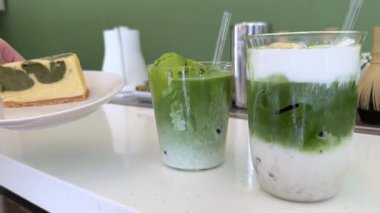 Matcha, Tayland 'daki Choui Fong Çay Çiftliği' nin ünlü turistik merkezinde bir masada buzlu yeşil çay, sütlü çay ve yeşil çay keki içer. Yüksek kalite 4k görüntü