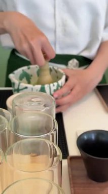 Bir barista matcha hazırlar, barutu pürüzsüz dairesel hareketlerle karıştırır. Yüksek kalite 4k görüntü