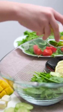 Salata standına salatalık ekle. Ebeveyn, ev hanımı ev mutfağında salata karıştırıyor. Modern anne yeşil salata hazırlar, farklı sebzeler ve sağlıklı beslenme kombinasyonları kullanır.