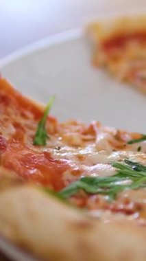 Strachatella peynirli jambonlu pizza, domates ve roka yapraklı. Tahta masada dönüyor. Yüksek kalite 4k görüntü
