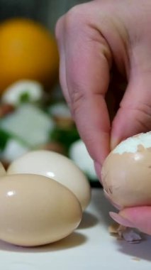 Haşlanmış yumurtayı nazikçe soyan bir kadının elleri besleyici bir atıştırmalık hazırlamanın basit ve tatmin edici sürecini gözler önüne seriyor. Yüksek kalite 4k görüntü