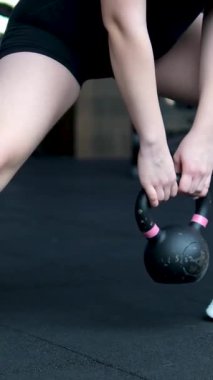 Spor kıyafetleri ve tesettürlü Müslüman bir kadın spor salonunda kettlebell ile ağırlık kaldırıyor. Yüksek kalite 4k görüntü