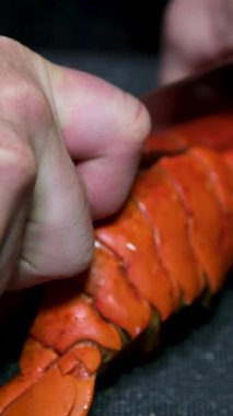 Kırmızı ıstakozu bıçaklayan ve 4K ile ikiye bölen bir şef. Bir ızgarayı marine etmek için koca bir ıstakozu iki parçaya bölme fikri. Yüksek kalite 4k görüntü