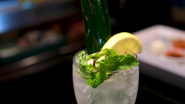 Koyu bir arka planda duran limon dilimli bir bardağa mavi kokteyl dökme sekansı. Yüksek kalite 4k görüntü