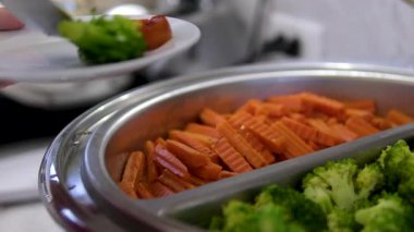 Gümüş kaşıkla servis kasesinde taze sebze servisi yapan brokoli havuçları. Tenderstem Brokoli, Havuç, Karnabahar, Bebek Mısır dahil. Doğal Işıkta Sağlıklı Yemek. Yüksek kalite 4k görüntü