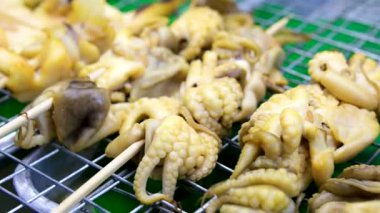 Tayland sokak satıcısının deniz ürünleri şiş ızgaralarını mürekkep balığı ve ahtapotla ızgarada pişirip aynı anda da Tayland, Güneydoğu Asya 'daki hareketli gece pazarında meşaleyle yakması. Mutfak