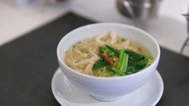 Buhar tüten bir kase Pho, geleneksel bir Vietnam şehriye çorbası, taze otlar, acı biberler ve sığır köfteleriyle süslenmiş. İştah açıcı et suyu ve canlı malzemeler lezzetli bir karışım yaratır. 