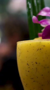 Tezgahta dönen bir bardak tekila kokteylinin yakın çekimi. Güzel bir kırmızı orkide çiçeğiyle mango chia tohumu kokteyli servis ediyorum.