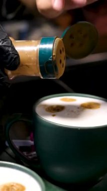 Adam kahveye tarçın ekliyor. Mutfaktaki bir restoranda yemek yapmak için.