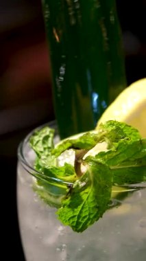 Koyu bir arka planda duran limon dilimli bir bardağa mavi kokteyl dökme sekansı. Yüksek kalite 4k görüntü