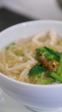 Buhar tüten bir kase Pho, geleneksel bir Vietnam şehriye çorbası, taze otlar, acı biberler ve sığır köfteleriyle süslenmiş. İştah açıcı et suyu ve canlı malzemeler lezzetli bir karışım yaratır. 