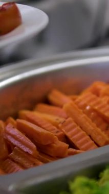 Gümüş kaşıkla servis kasesinde taze sebze servisi yapan brokoli havuçları. Tenderstem Brokoli, Havuç, Karnabahar, Bebek Mısır dahil. Doğal Işıkta Sağlıklı Yemek. Yüksek kalite 4k görüntü