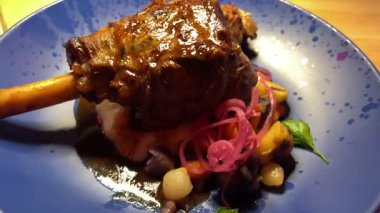 Etin üzerine kaşık sosu dök. Pişmiş kuzu budu. Kuzu etine koyu kırmızı sos ve salata. Şarabı ve yemek programı olan şefler masası. . 