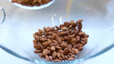 Badem unu, arka planda badem fıstığı olan cam bir kaseye dökülür. Yüksek kalite 4k görüntü