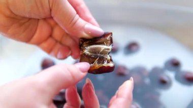 Olgun bir tarihi soyan, yumuşak ve tatlı etini ortaya çıkaran ellerin yakın çekimi. Yemek, beslenme ve Orta Doğu mutfağı teması için mükemmel. Yüksek kalite 4k görüntü