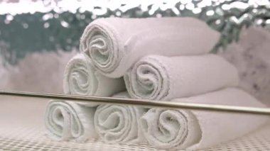 Gri arka planda beyaz masanın üzerinde duran birkaç beyaz katlanmış havlunun 4k stok video görüntüsü. Kadın üç pamuk havluyu istifliyor. Yüksek kalite 4k